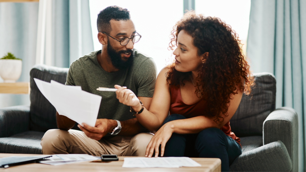 A couple examining documents while sitting on a sofa, exploring the Battery Storage Technology Tax Credit to maximize savings.