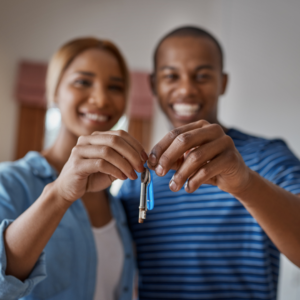 A smiling couple holding up a key together, symbolizing a new home or solar ownership